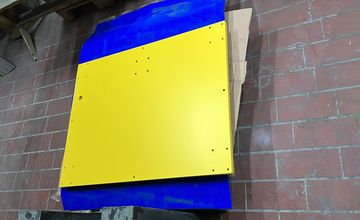 Gelb und blau beschichtete Plattenbauteile als Referenzarbeit